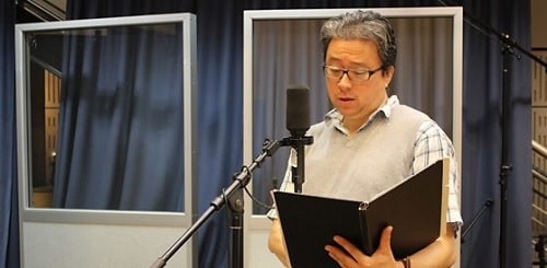 A picture of Paul Courtenay Hyu reading script.